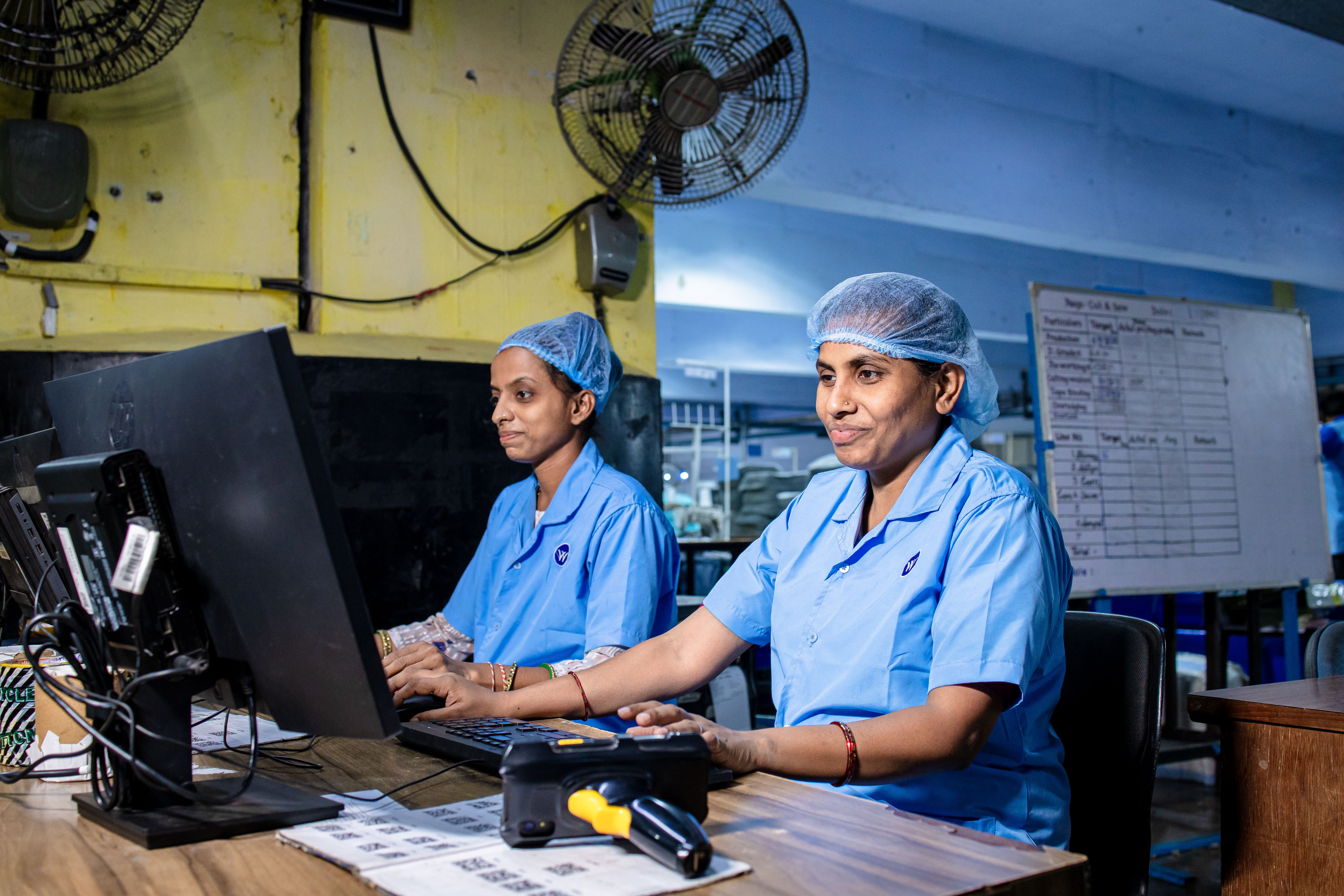 Two operators at a desk with a barcode scanner and QR labels